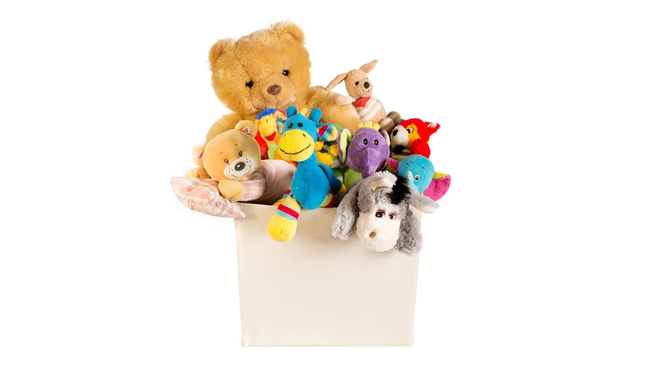 Collection of plushies in a cream box, with a large teddy bear in the background surrounded by smaller plushies including teddy bears, a donkey, a blue dragon, a purple elephant and a red fox.