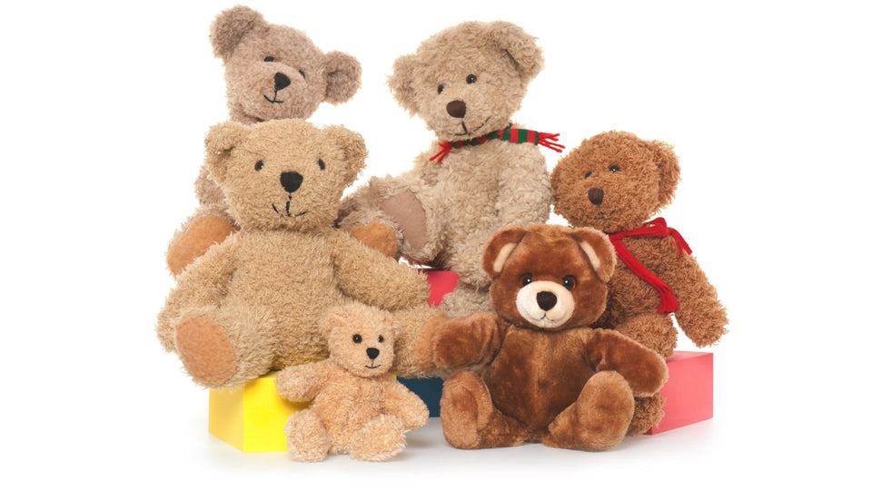 Collection of soft toy teddy bears of various sizes. There are six in total ranging from a small teddy bear through to a couple of much larger teddy bears. One bear on the left sits in a yellow box and the right bear sits on a red box.